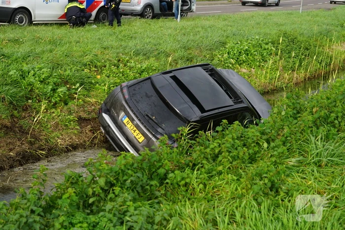 Omstanders halen inzittenden uit te water geraakt voertuig
