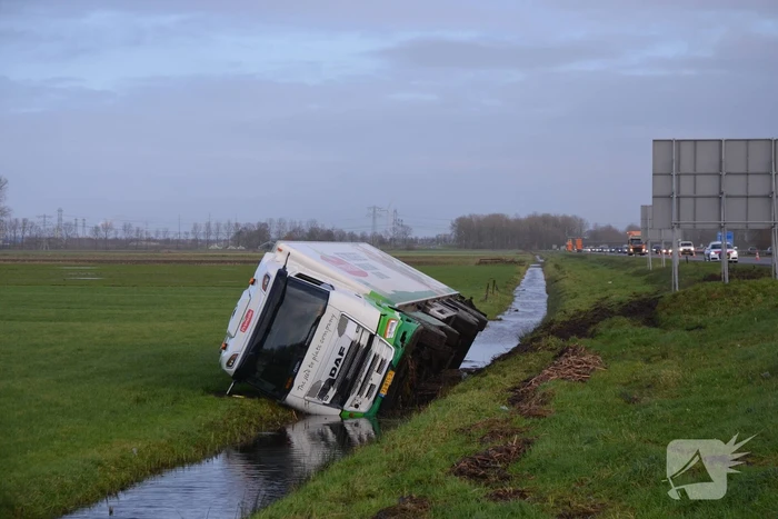Vrachtwagen gekanteld in sloot naast snelweg
