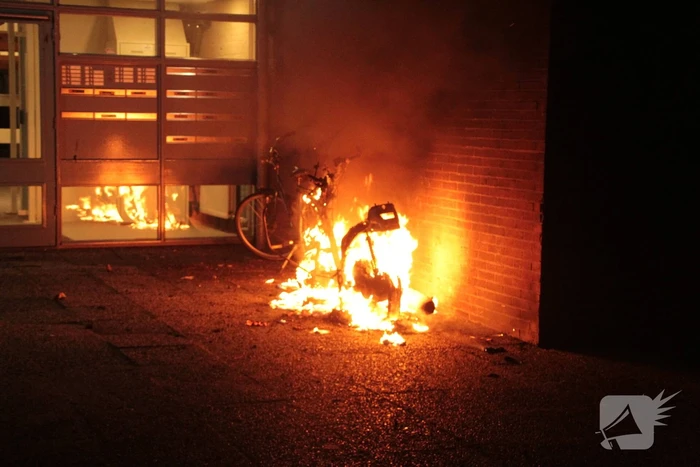 Brandweer blust brandende scooter tegen appartementencomplex