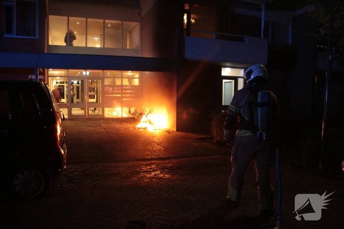 Brandweer blust brandende scooter tegen appartementencomplex