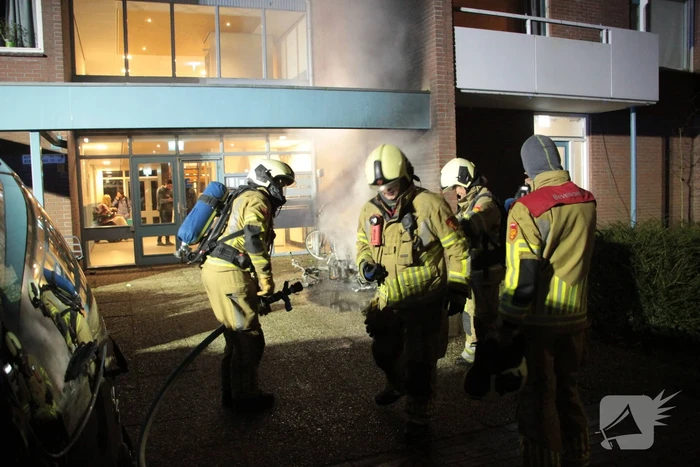 Brandweer blust brandende scooter tegen appartementencomplex