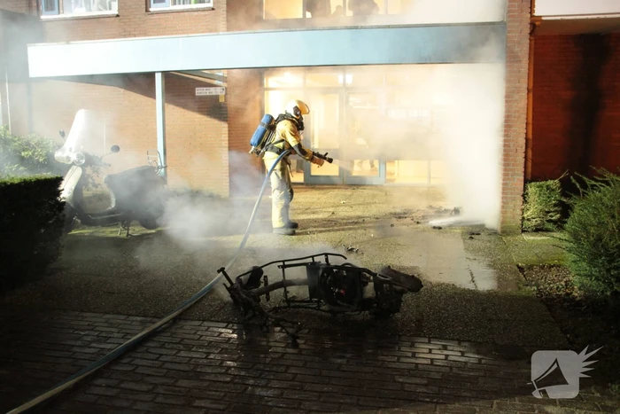 Brandweer blust brandende scooter tegen appartementencomplex