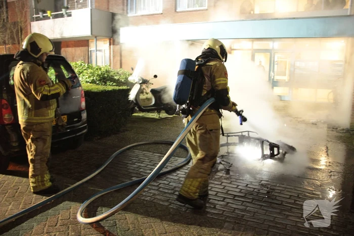 Brandweer blust brandende scooter tegen appartementencomplex