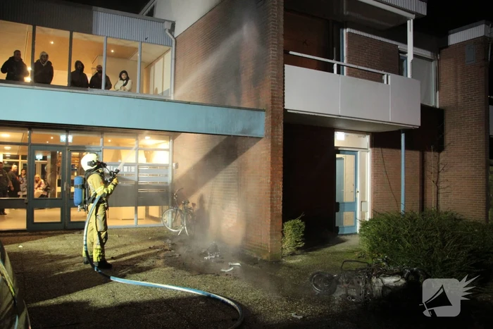 Brandweer blust brandende scooter tegen appartementencomplex