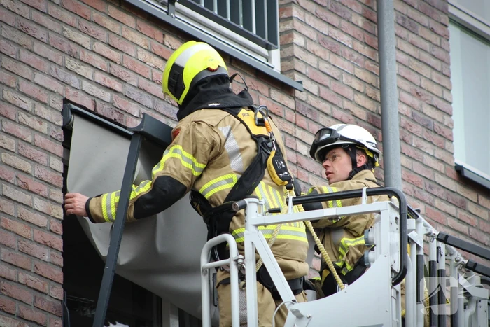 Brandweer zet loshangende zonnescherm vast