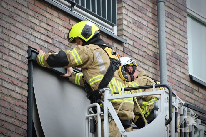 Brandweer zet loshangende zonnescherm vast