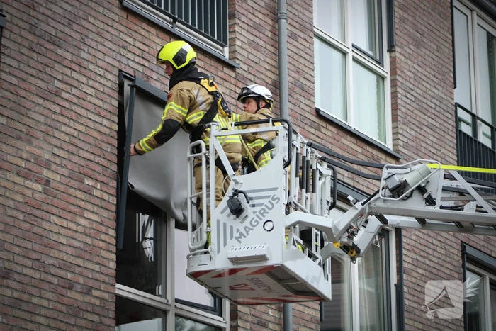 Brandweer zet loshangende zonnescherm vast