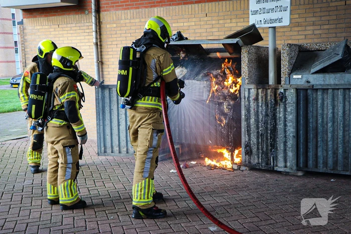 Containers onder flatgebouw in brand