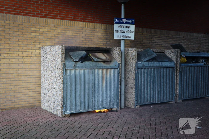 Containers onder flatgebouw in brand
