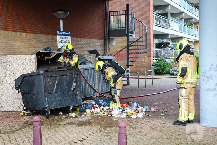 Containers onder flatgebouw in brand