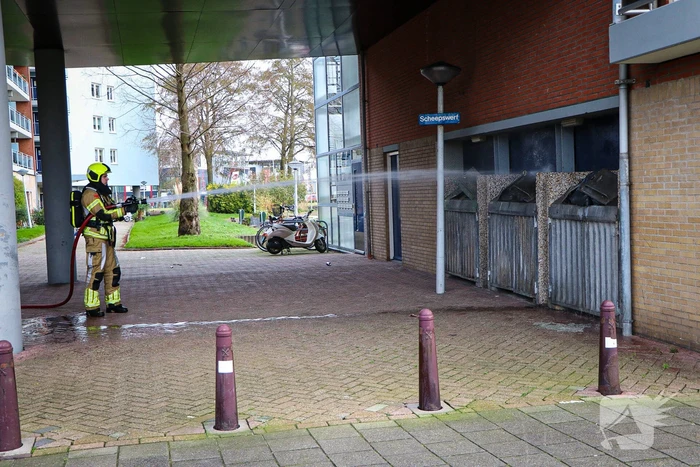 Containers onder flatgebouw in brand