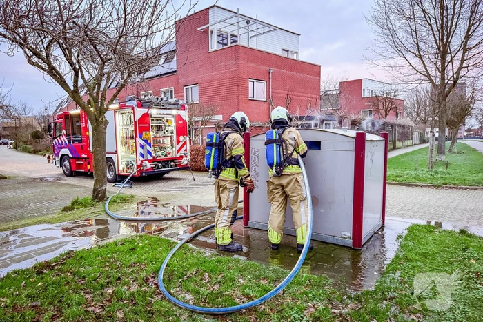 Brandweer blust brandende papiercontainer