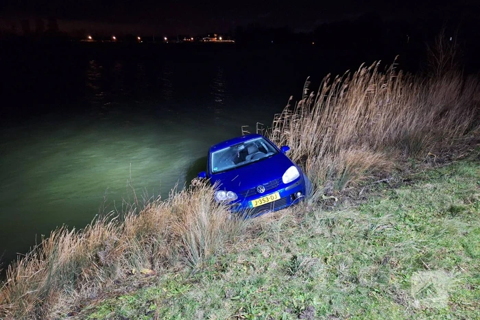 Auto met twee inzittenden rolt water in tijdens 