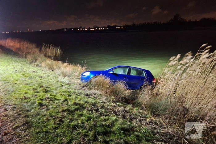 Auto met twee inzittenden rolt water in tijdens 