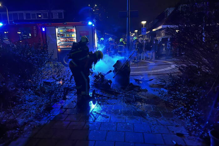 Brandweer blust brandende vuurton en scooter