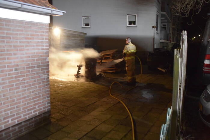 Brandweer blust brandende vuurton in achtertuin