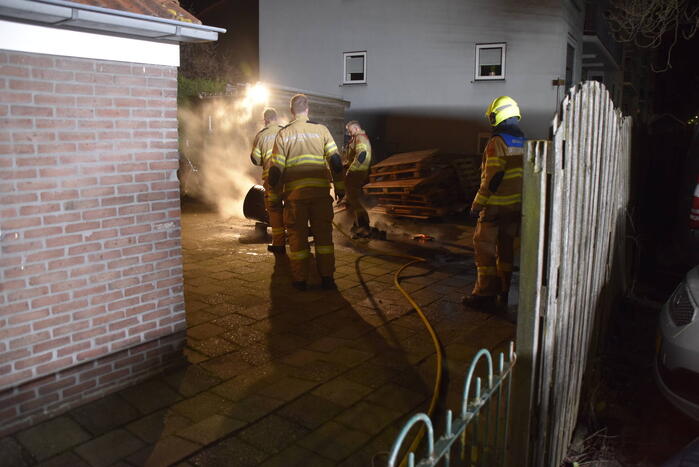 Brandweer blust brandende vuurton in achtertuin