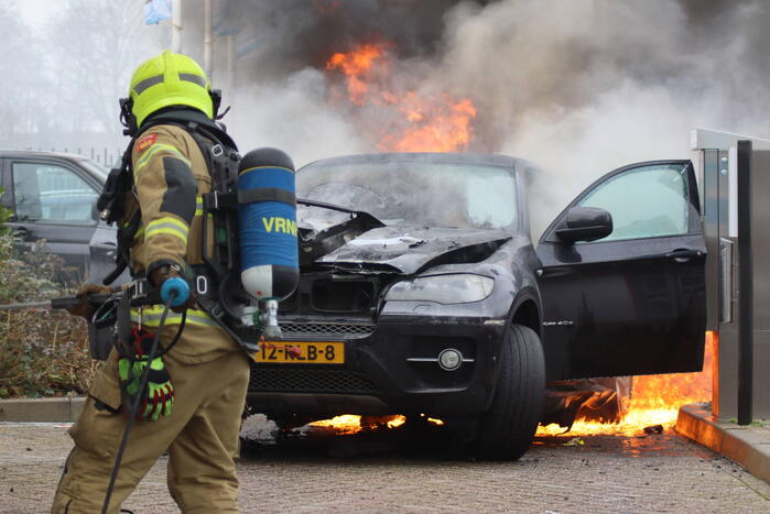 Auto vliegt in brand voor ingang carwash