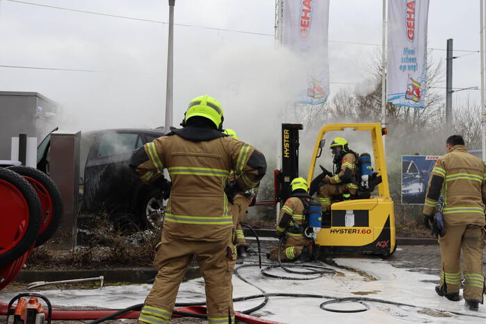 Auto vliegt in brand voor ingang carwash
