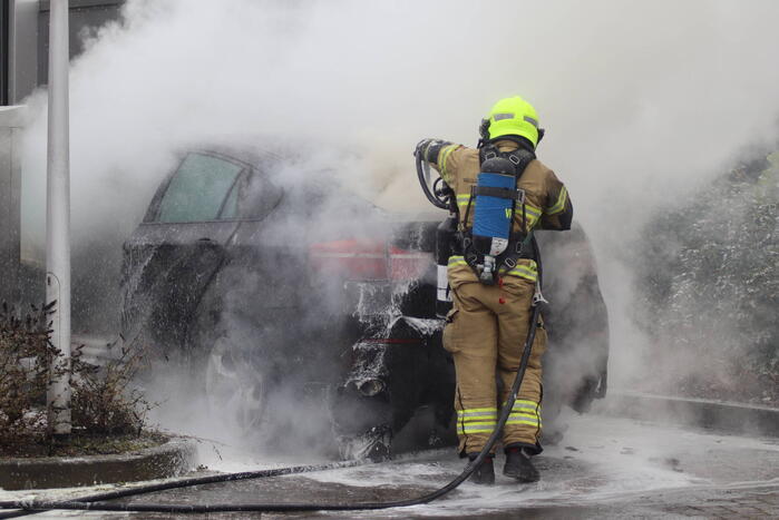 Auto vliegt in brand voor ingang carwash