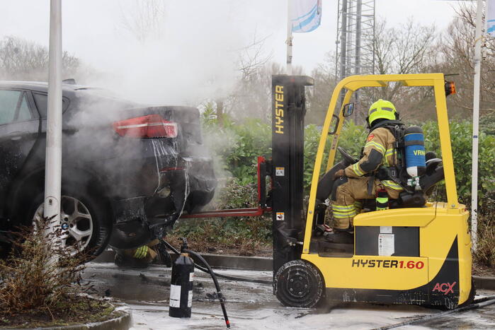 Auto vliegt in brand voor ingang carwash