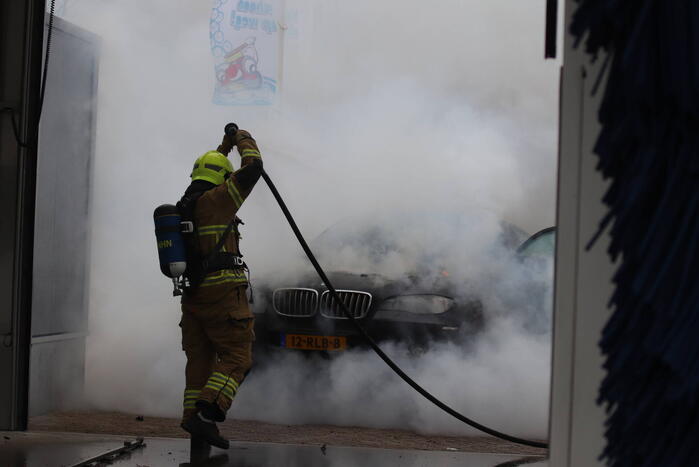 Auto vliegt in brand voor ingang carwash