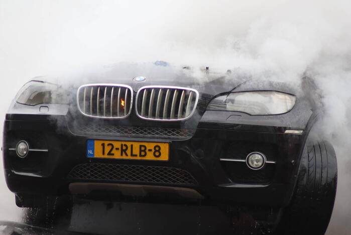 Auto vliegt in brand voor ingang carwash