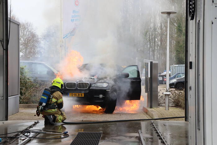 Auto vliegt in brand voor ingang carwash