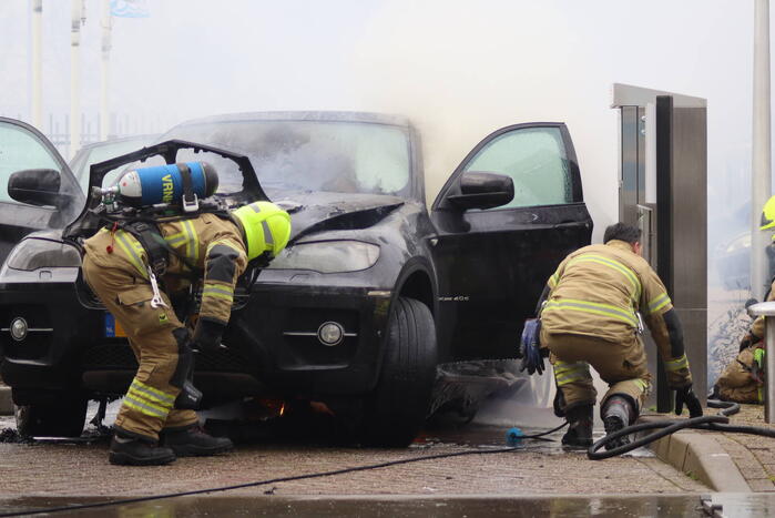 Auto vliegt in brand voor ingang carwash