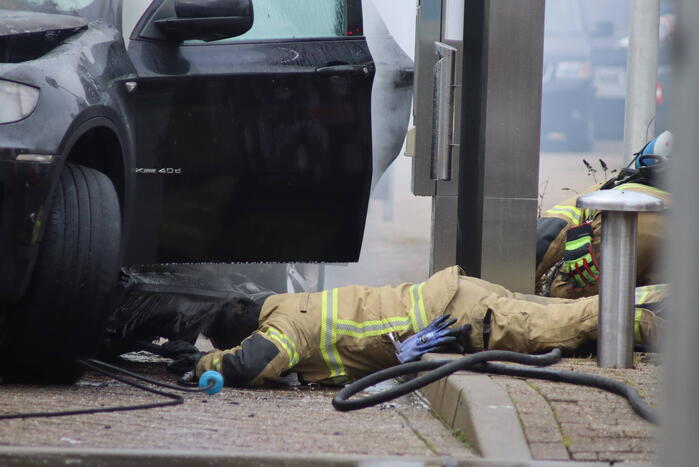 Auto vliegt in brand voor ingang carwash
