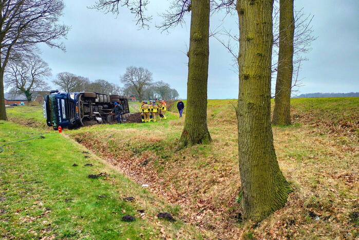 Vrachtwagen belandt op zijn kant naast de weg