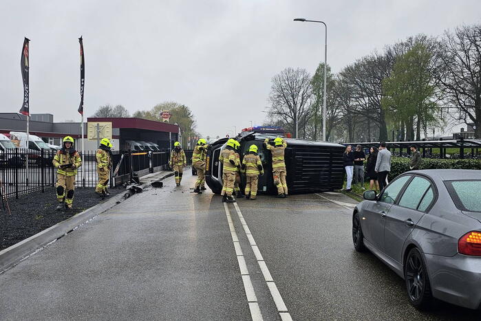 Bestelbus botst op hek en belandt op zijkant
