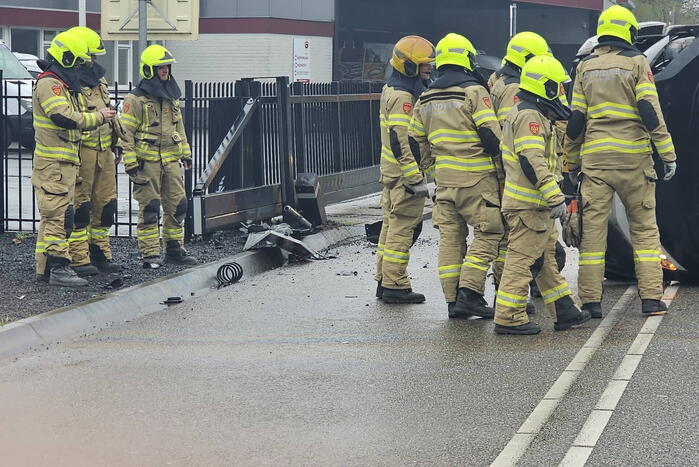 Bestelbus botst op hek en belandt op zijkant