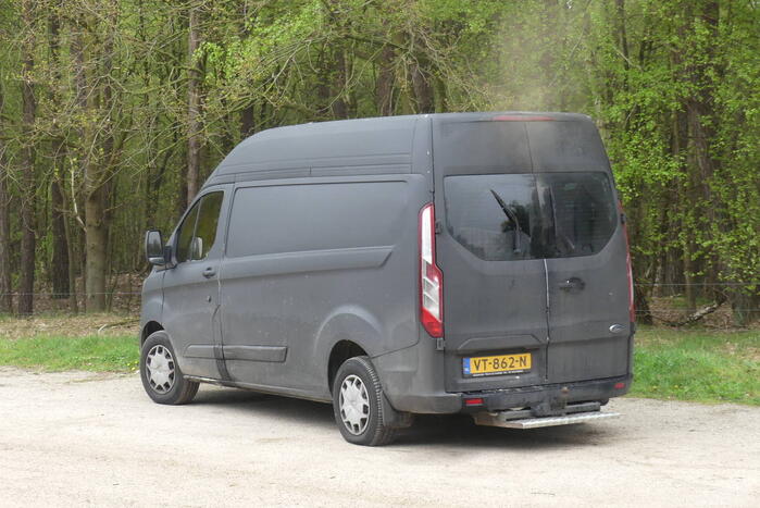 Bestelbus met afval in brand gestoken op parkeerplaats bij bos, twee aanhoudingen