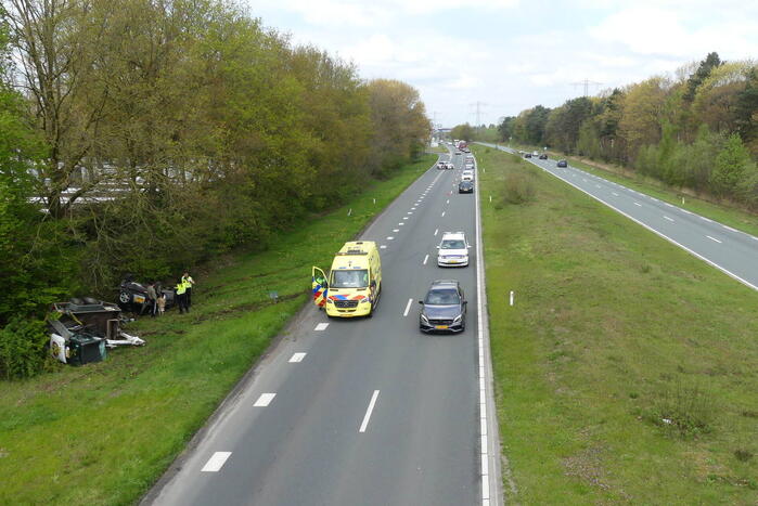 Auto en aanhanger met graafmachine over de kop