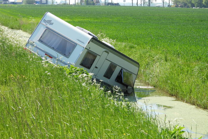 Caravan raakt los van auto en belandt in sloot