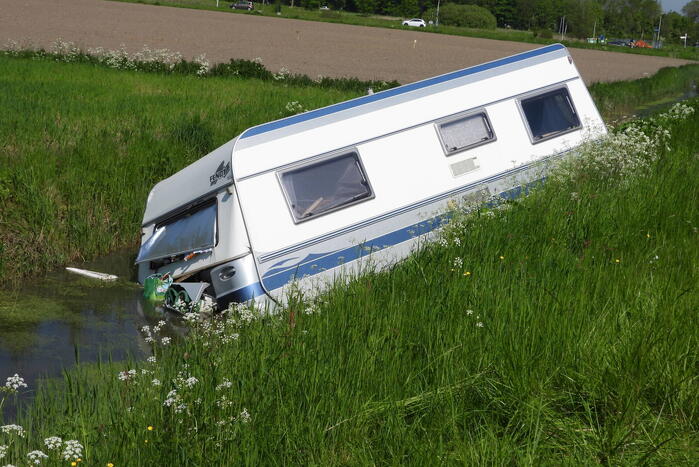 Caravan raakt los van auto en belandt in sloot