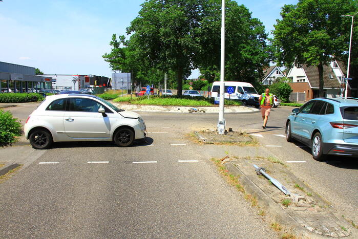 Automobilist ramt paal en lantaarnpaal bij rotonde