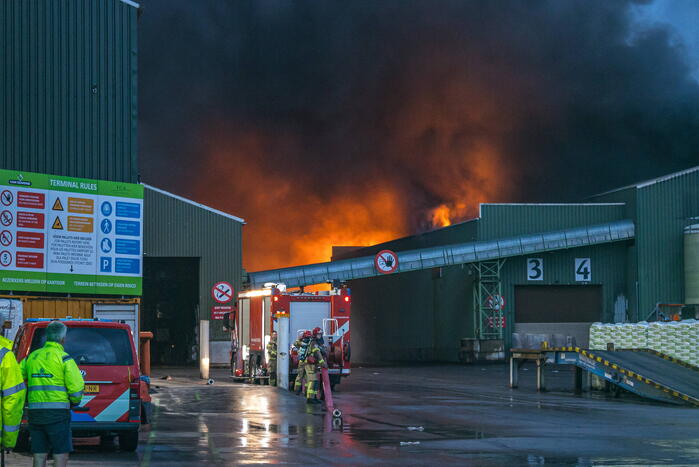 Zwarte rookpluimen boven havengebied door grote brand