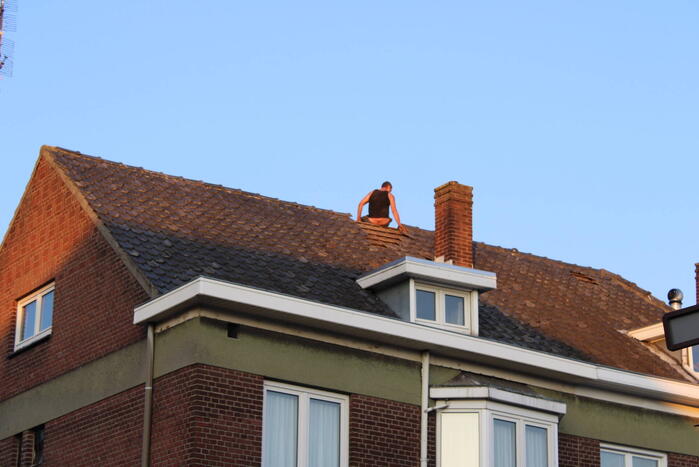 Man klimt op woning en gooit dakpannen naar hulpdiensten