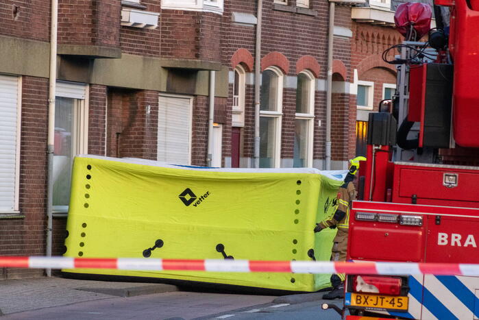Man klimt op woning en gooit dakpannen naar hulpdiensten