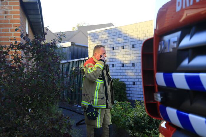 Brandweer blust brandende prullenbak in schuur