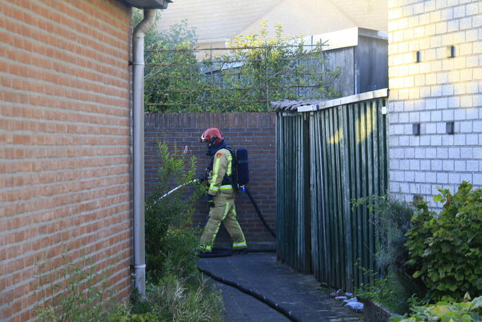 Brandweer blust brandende prullenbak in schuur