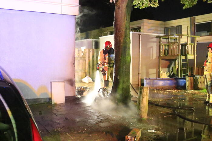 Scooter in brand tegen woning