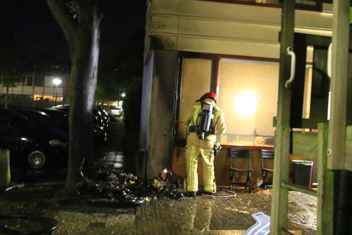Scooter in brand tegen woning