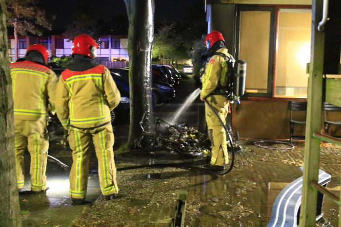 Scooter in brand tegen woning