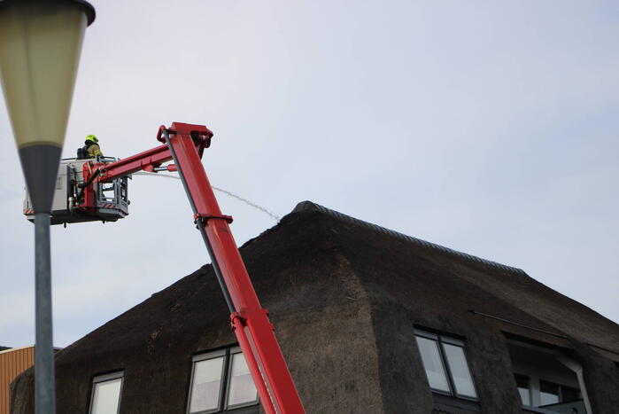 Brand op dak van appartementencomplex met rietendak
