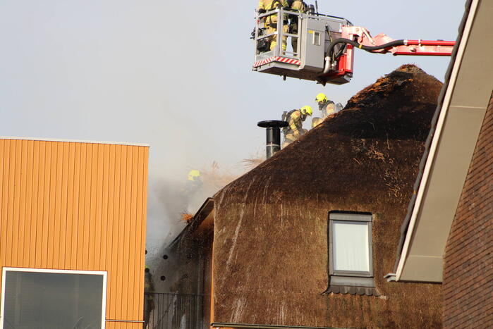Brand op dak van appartementencomplex met rietendak