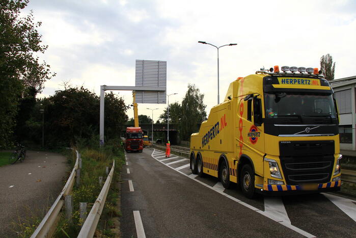 Vrachtwagen geladen met betonplaten vast onder spoorbrug