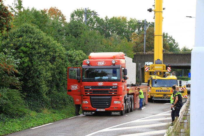 Vrachtwagen geladen met betonplaten vast onder spoorbrug